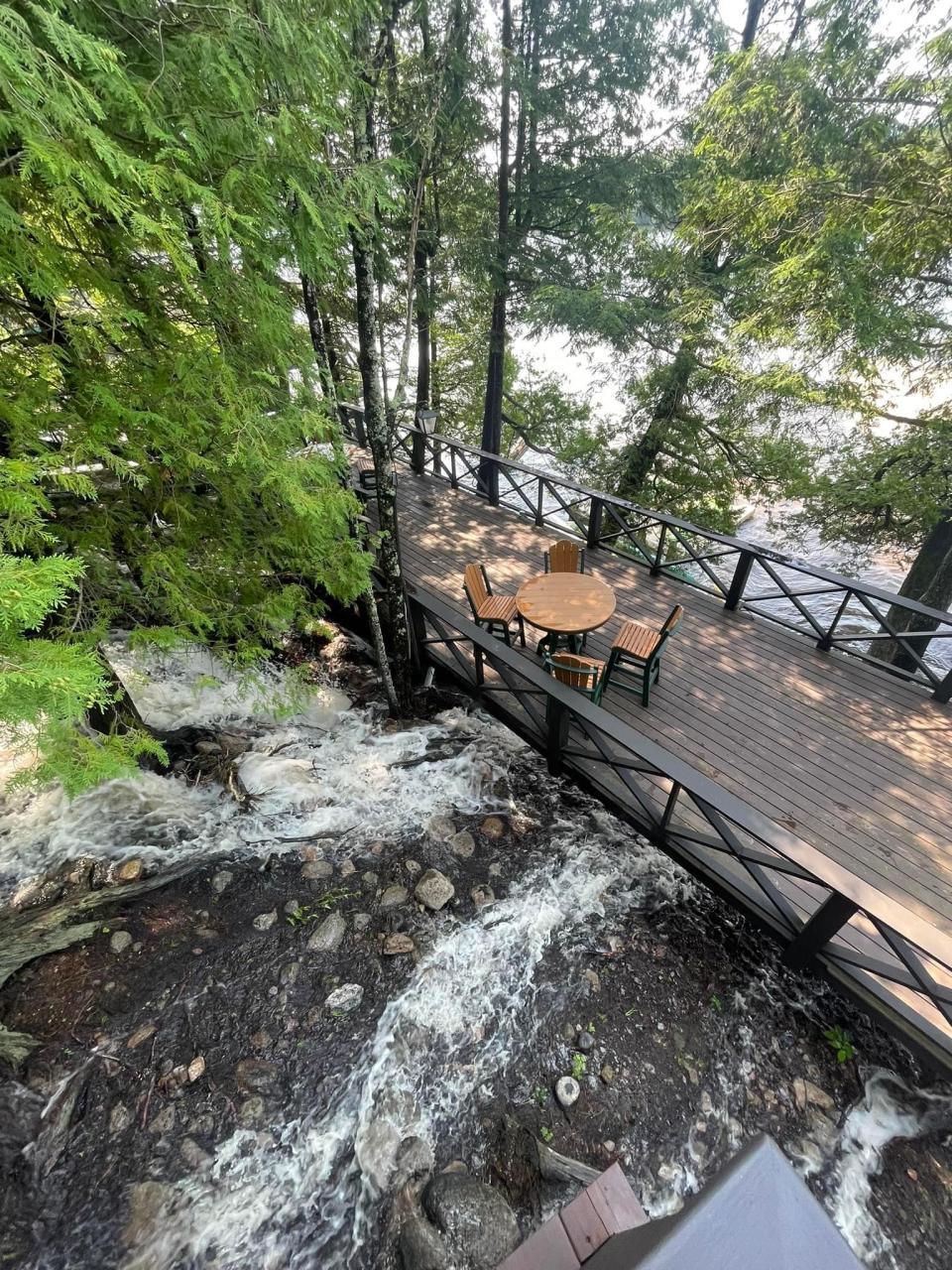 A bridge with a table and chairs over a rushing river.