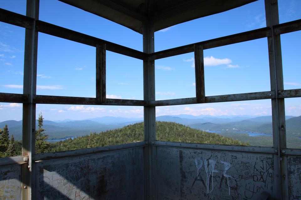A view from a fire tower of nearby green mountains.