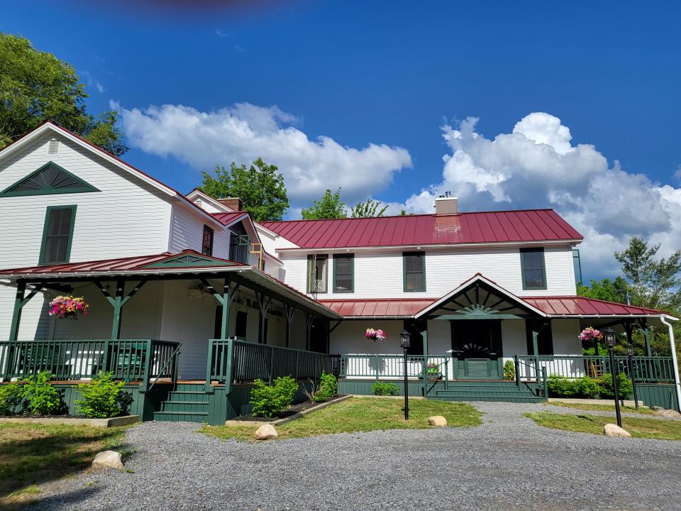 white historic inn with green trim and a metal roof