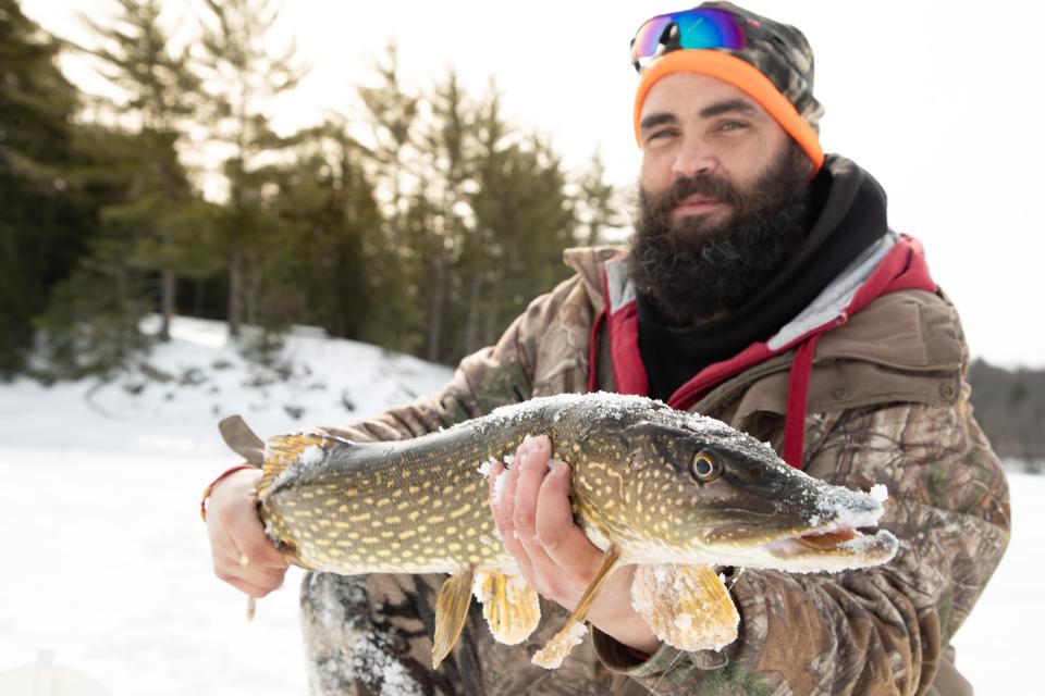 A man holds a northern pike at an ice fishing derby in Hamilton County