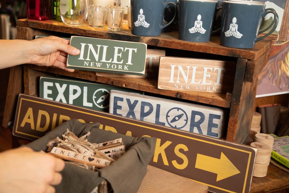 Close-up of rustic wooden signs reading, "Inlet," "Explore," and "Adirondacks."