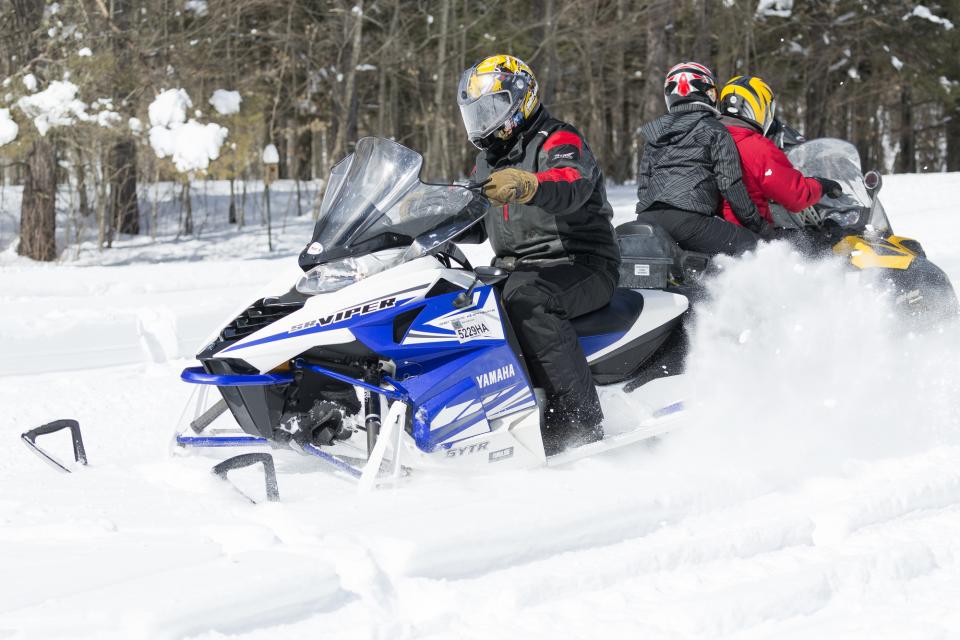 Two snowmobiles pass each other on a trail.