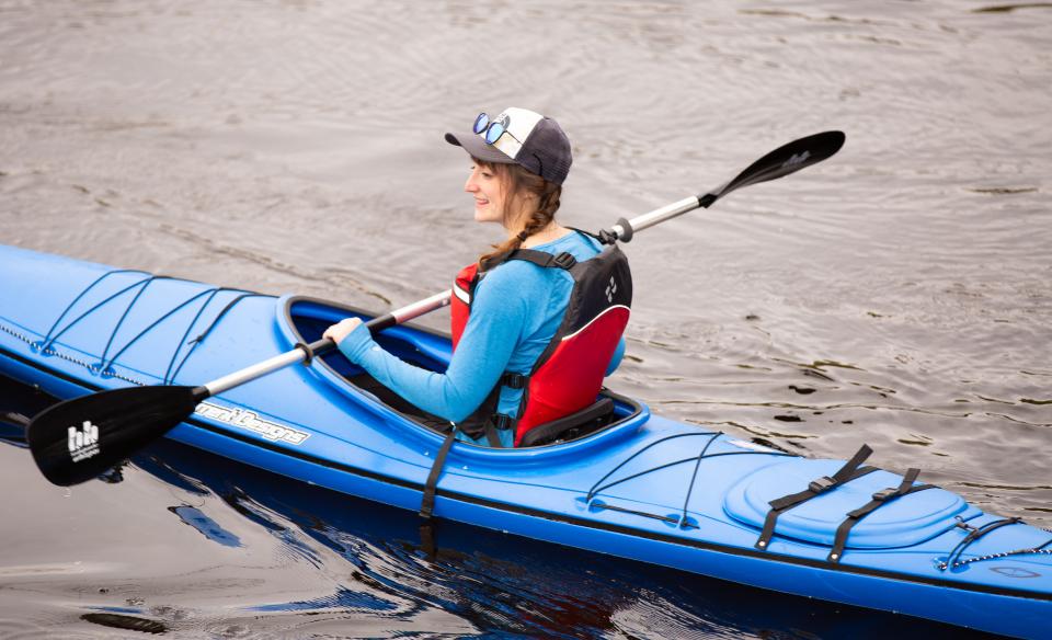 A woman paddles in a blue kayak.