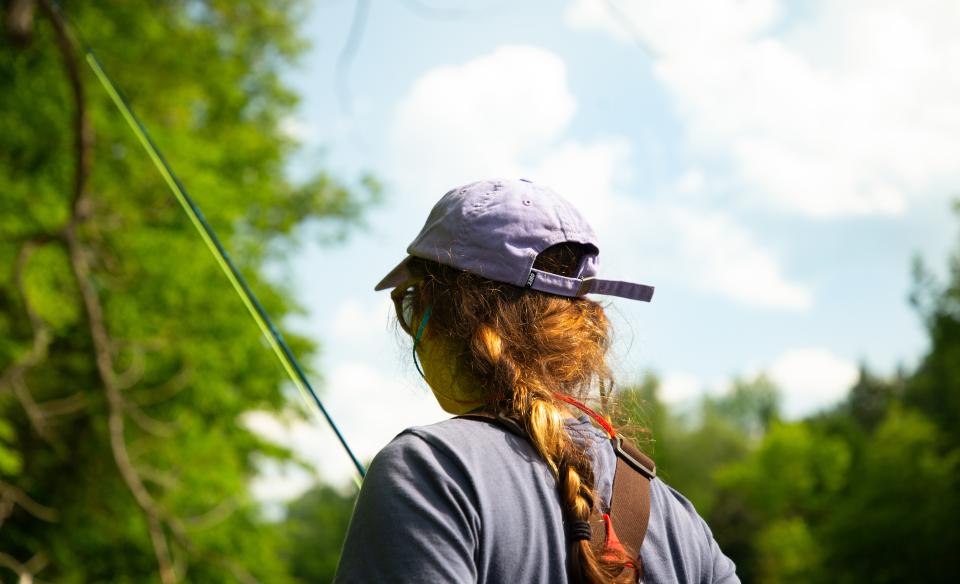A woman holds a fishing pole.