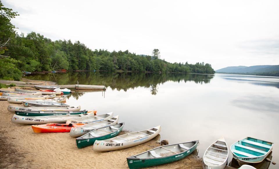 A beach full of rental kayaks and canoes on the shore of a beach at Lewey Lake.