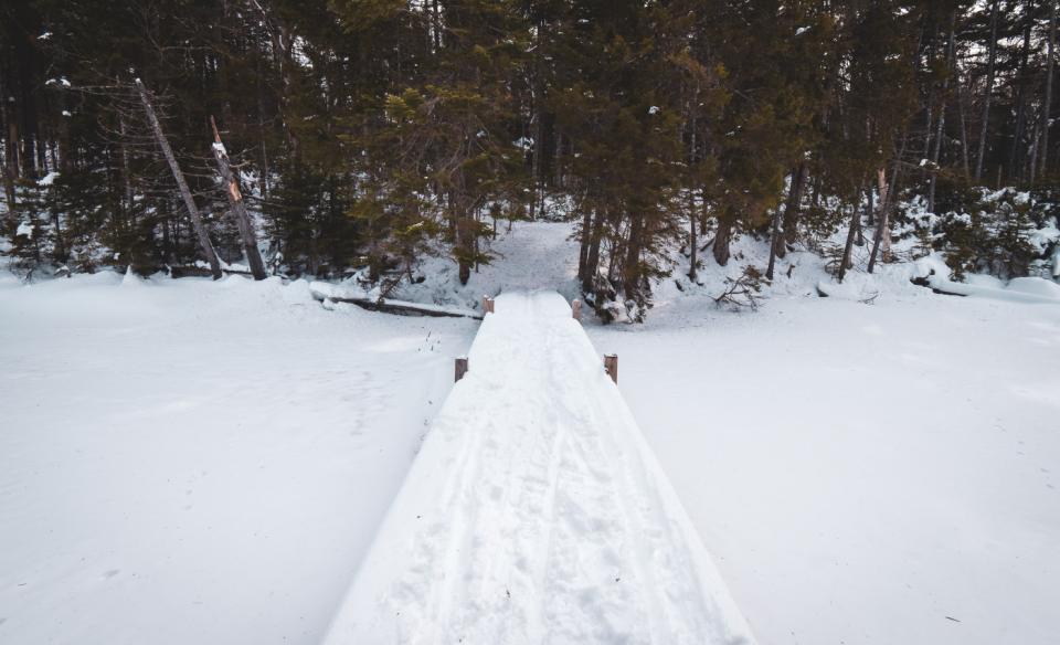 A snow-covered wooden walk bridge